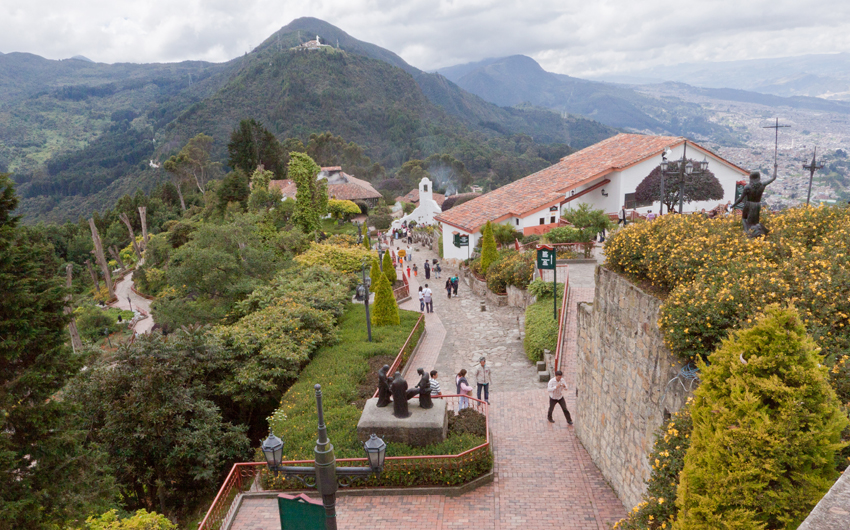 Tourists at Monserrate Hill with yellow blooming flowers and its historical buildings, Bogota