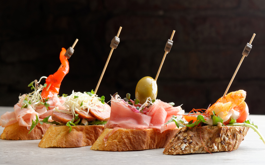 Selection of Spanish tapas served on a sliced baguette