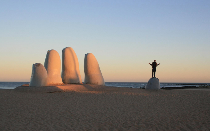 Big hand on the beach, sunset at the beach, person above finger, sea cost blue sky uruguay punta del este giant sand ocean